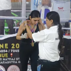 The moment of victory. A referee awards the gold medal after a hard-fought win in the kickboxing championship.