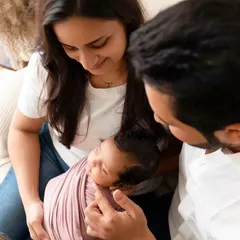 A quiet, intimate moment with parents gazing at their swaddled newborn. These lifestyle shots capture the overwhelming love and connection in a new family.