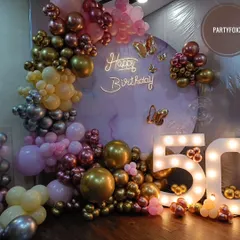 An elegant 50th birthday setup with a mix of chrome, rose gold, and pastel pink balloons, a custom backdrop, and large marquee numbers.