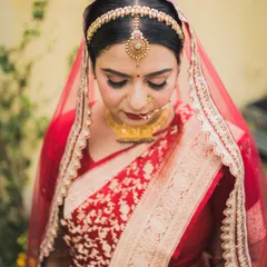 A moment of quiet reflection for the bride, Aditi, in her beautiful red Banarasi saree. Her traditional jewelry and serene expression are timeless.