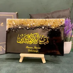 This personalized plaque features the verse "Fabi ayyi ala i rabbikuma tukazziban" in bold yellow calligraphy on a black background. The top is adorned with a textured mix of gold and silver embellishments, and it includes the client's name for a personal touch.