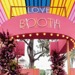 A fun and interactive 'Love Booth' at the Haldi event, adorned with flowers and neon signs for the perfect photo opportunity.