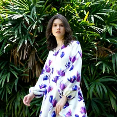 A model in a breezy, floral print mini dress with balloon sleeves. The movement in her pose and the sunny backdrop perfectly capture the carefree spirit of summer.