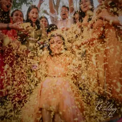 A bride being showered with love and flower petals during her Haldi ceremony. These are the joyful, candid moments that make Indian weddings so special.