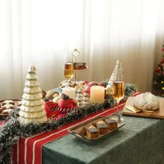 A beautifully decorated Christmas table spread, complete with a tree, candles, and a variety of festive bakes. This wide shot sets a magical holiday scene.