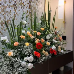 A lush and vibrant floral arrangement designed to beautify a console table for a housewarming party. The mix of red, orange, and white flowers adds a burst of color and joy to the home.