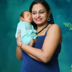 A mother holds her newborn baby close, both set against a rich teal background. A simple, beautiful portrait.