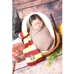 The magic is real with our Harry Potter inspired newborn shoot. Your little one becomes the newest student at Hogwarts, complete with a Gryffindor scarf, round glasses, and a magic wand, all set for a fantastical journey.