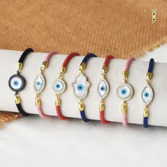 Tie the bond of love and protection with my evil eye rakhis. This image shows a variety of thread bracelets with different evil eye and hamsa designs.