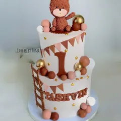 A charming two-tier woodland teddy bear cake for Tashvin's first birthday. The neutral brown and beige tones, along with the cute bear topper, create a warm and rustic feel.