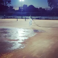 Our staff performs daily maintenance, watering the courts under the lights to ensure they are in perfect condition for the next day's sessions.