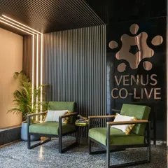 This cozy conversation nook at Venus Co-Live uses comfortable armchairs, warm lighting, and textured wall panels to create an inviting corner for informal chats or a quiet moment away from the main work floor.