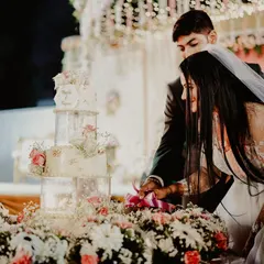 The cake cutting ceremony is the first sweet task a couple performs together. This shot captures that moment, surrounded by a beautiful floral arrangement, marking the start of their sweet new life.