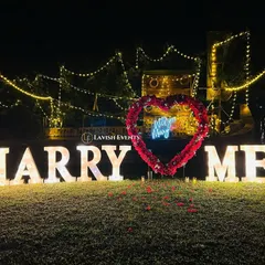 Setting the stage for a 'yes'. This romantic proposal setup with giant marquee letters and fairy lights is all about creating that magical moment you've always dreamed of.