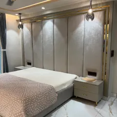A master bedroom designed for rest and elegance. The custom-made upholstered headboard with gold metal inlay, combined with soft cove lighting and pendant lights, creates a sophisticated and serene environment.