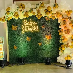 A clear view of the green wall backdrop for the baby shower, perfect for photos. The setup includes 'BABY' blocks and spotlights.