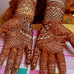 A beautiful example of symmetrical bridal mehendi. Both hands mirror each other with intricate check patterns and delicate floral work, creating a harmonious and balanced design.