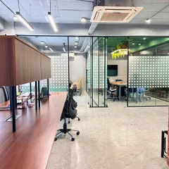 An overview of the open-plan office, with glass partitions creating a sense of transparency. The design combines sleek workstations with an industrial-style exposed ceiling for a modern and efficient workspace.