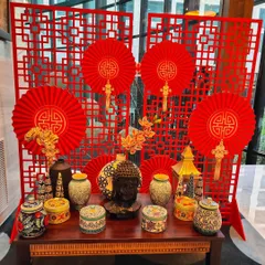 A beautifully styled console table for a Hakka Chinese Cuisine Food Festival. The setup includes a red lattice backdrop, paper fans, and a collection of ceramic jars and a Buddha head, creating an authentic and visually rich display.
