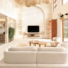 The heart of the Artha Villa project is this double-height living space, designed to feel both grand and intimate. Natural light floods the room, highlighting the earthy textures, woven rattan lighting, and an open-concept layout that connects directly to the outdoors.
