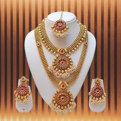 This complete bridal jewelry set is perfect for your big day. It includes two layered necklaces with red stone and pearl details, matching earrings, and a maang tikka to finish the look, all available for rent in Bangalore.