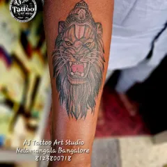 A fierce roaring lion tattoo on the forearm, complete with a tilak. This design represents power, courage, and divinity.
