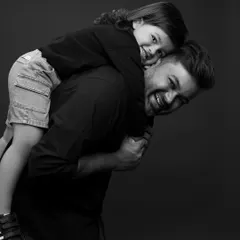 A piggyback ride from dad is always a good idea. The genuine smiles in this black and white portrait are what it's all about.