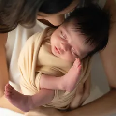 A mother's gentle kiss for her sleeping baby. This overhead shot focuses on the baby's tiny, perfect features and the incredible sense of peace they bring.