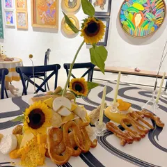 A close-up of the edible art installation, showing the combination of sunflowers, various cheeses, and pretzels.