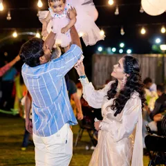 A father joyfully lifts his daughter in the air during her first birthday party. These are the candid, happy moments we love to see.