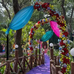 A colourful floral archway over a purple carpeted bridge. This pathway was designed to lead guests into the main carnival area, building anticipation with every step.