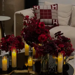 For a luxurious home birthday, we created a dramatic atmosphere using masses of crimson flowers and glowing candles on mirrored and metallic surfaces to reflect the light beautifully.