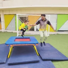 Our instructors are partners in every child's journey of discovery. A trainer joins a young camper on the trampoline, demonstrating our hands-on approach to teaching and ensuring every child feels supported and confident.