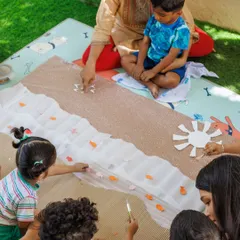 Children work together on a large-scale art project, creating a beach scene. Collaborative art teaches teamwork and communication, as they negotiate space and share materials to achieve a common goal.