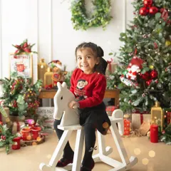 A classic childhood moment on a rocking horse, set against a backdrop of twinkling Christmas lights. These are the memories that make the holidays special.