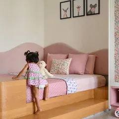 The daughter's bedroom in 'Cover me in Sunshine' is a blush haven. The custom platform bed features a playful, wavy upholstered headboard and is designed to be accessible for a toddler.