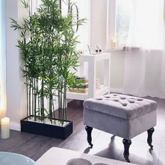 A tall bamboo plant in a sleek black planter serves as an elegant and natural room divider. This is a simple yet effective way to create separation in a space while maintaining a light and open atmosphere.