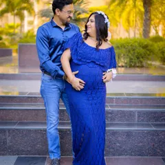 A full-length portrait of the couple during their outdoor maternity shoot. The vibrant blue dress stands out beautifully against the natural background.