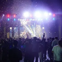 The grand finale of a New Year's Eve event. A wide shot of the stage, lights, confetti, and the massive crowd celebrating the start of a new year.