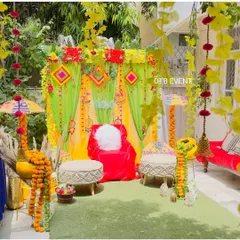 This outdoor Mehendi decor is one of my favorites. The setup includes a bright green and yellow draped backdrop, comfortable seating, and traditional props like decorated matkas and umbrellas.