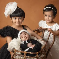 The first meeting between siblings is pure magic. Here, two proud big sisters watch over their sleeping newborn brother, creating a beautiful, tender memory of their new family dynamic.