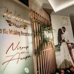 A grand and personalized welcome for a wedding reception. This setup features a large welcome sign with the couple's names, their monogram, and a beautiful pre-wedding photo.