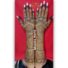 This bridal back-hand design is rich with detail, featuring dual-tone effects, lotus motifs, and fine check patterns that extend to the elbows.