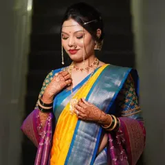 A traditional Maharashtrian bridal portrait. The focus is on the intricate details, from the 'mundavalya' on her forehead to the bold red lip, creating a look that is both timeless and regal.