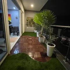This urban balcony is now a chic, modern retreat. We combined stylish wood-composite deck tiles with patches of artificial turf and elegant planters to create a beautiful and low-maintenance outdoor space.