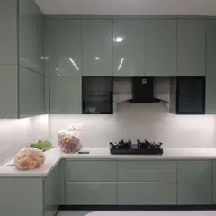 A look at a recently completed modular kitchen featuring a serene sage green palette with a high-gloss finish. This design showcases our factory-finished precision, complete with handleless cabinets, integrated appliances, and under-cabinet lighting for a clean, functional, and modern culinary workspace.
