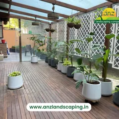 Another perspective of the Good Earth Malhar sunroom, showing the spacious layout on the wooden deck. The hanging baskets and large potted plants turn this glasshouse into a true botanical retreat.