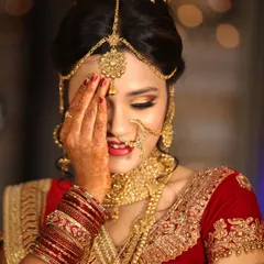 A candid and shy smile from a bride in her gorgeous red and gold wedding lehenga.