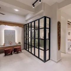A stylish glass partition separates the bar area from the pooja space in 'Project Lily', creating distinct zones while maintaining an open feel.