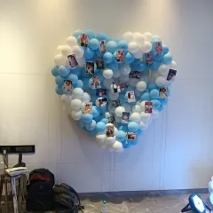 A heart-shaped balloon wall created with blue and white balloons. This unique installation was used as a photo collage board, allowing the family to display precious pictures of their little one.